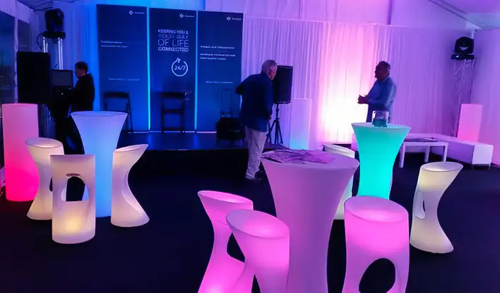 A group of colorful stools and tables in a tent.