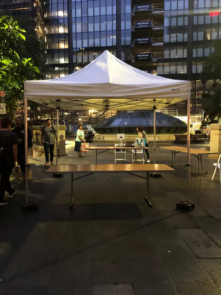 A white tent with tables and chairs in the middle of a city.