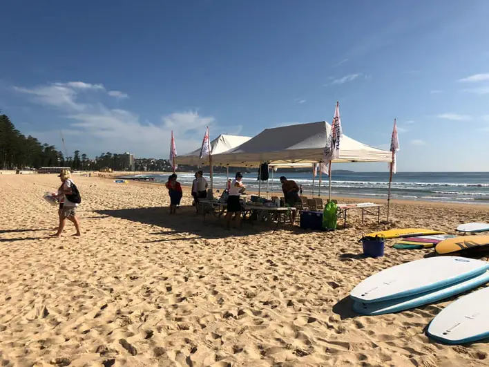 A group of people standing on the beach with surfboards.