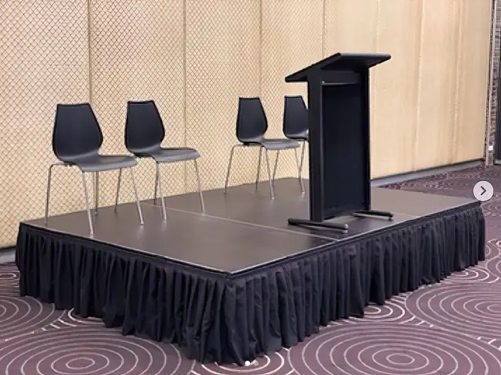 A podium with four chairs and a podium stand.