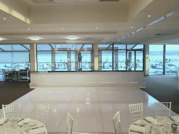 A room with white tables and chairs and a view of the ocean.