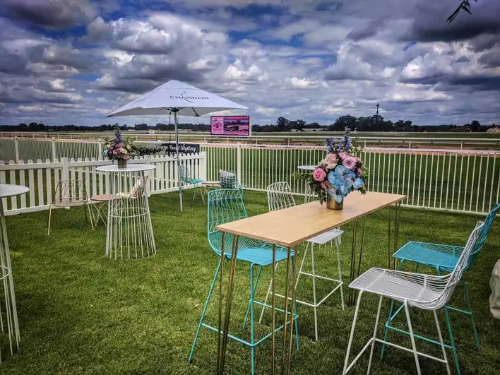 A table and chairs in a grassy area at a race track.