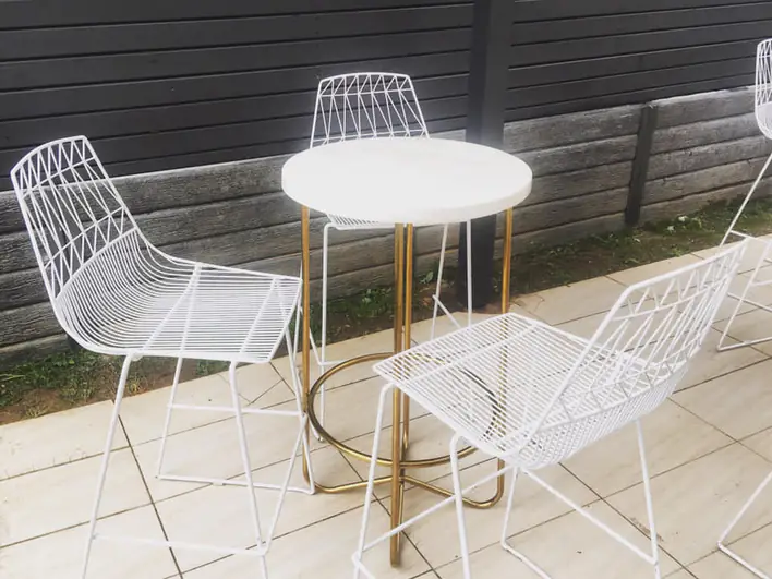 A set of white stools and a table on a patio.