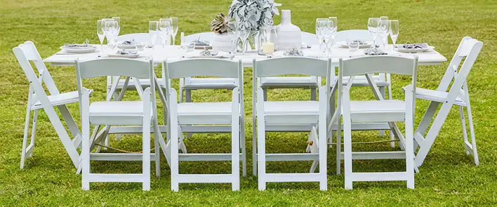A white folding table set up on a grassy field.