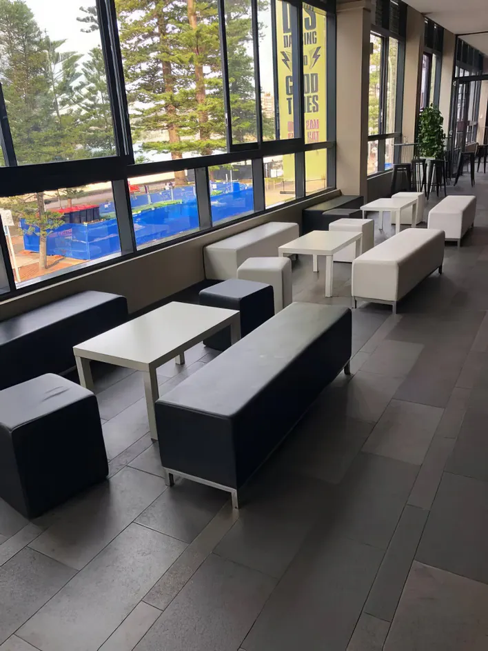 A group of black and white benches in a room with large windows.