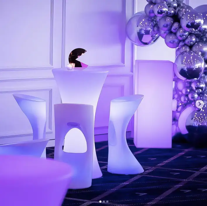 A purple table and chairs in a room with purple balloons.