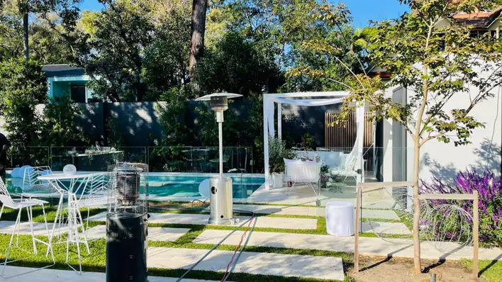 A backyard with a pool and white furniture.
