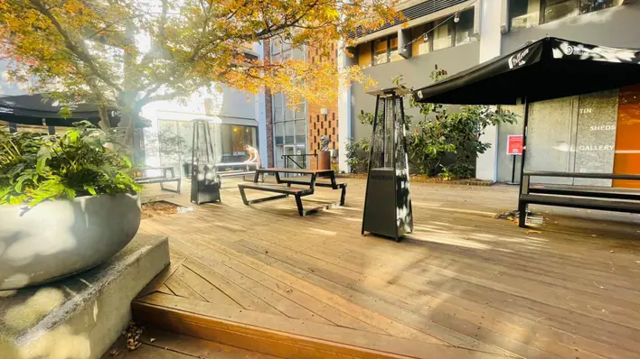 A wooden deck with tables and chairs in front of a building.
