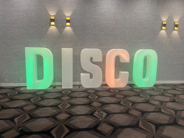 An illuminated disco sign in a room.