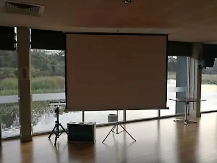 A room with a projector screen in front of a window.