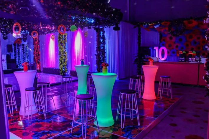 A party room decorated with colorful lights and stools.