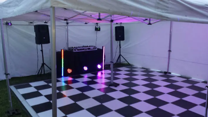 A tent with a checkered floor and dj equipment.