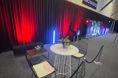 Black event draping with red uplighting behind a lounge and cocktail seating area in an indoor event venue