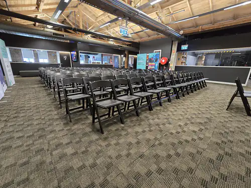 Lots of black plastic chairs set up for a conference