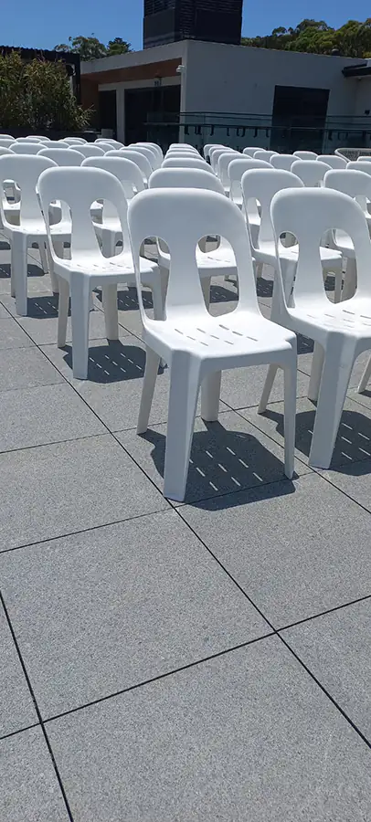 Lots of white stackable chairs set up at an outdoor conference