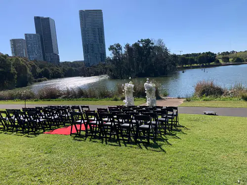 Scores of black plastic folding chairs for an outdoor event in front of a river