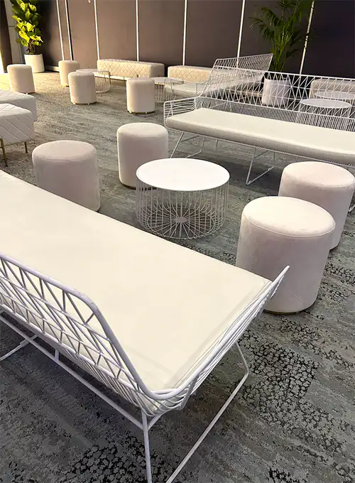 White wire sofa lounges with white ottomans on a carpeted floor
