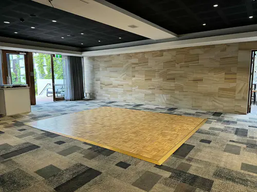 Indoor function venue with parquetry dance floor positioned in an open event space with patterned carpet flooring