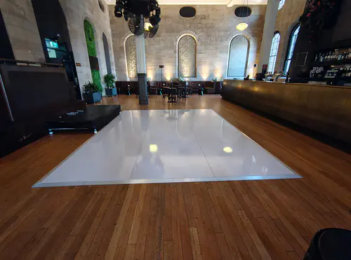 White gloss dance floor installed inside an elegant function venue with timber flooring and stone feature walls