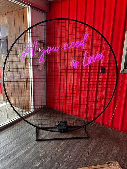 A black mesh backdrop with a neon sign on it