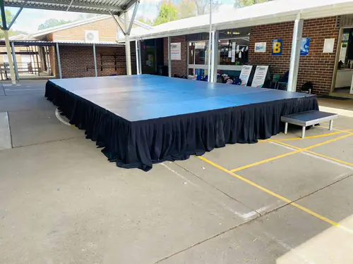 Indoor event stage platform with black skirting set up in a function space for presentations or speeches