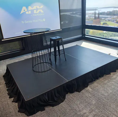 Small presentation stage with podium, screen and high table set up in a corporate meeting room with city views