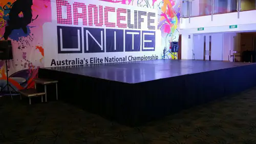 Wide stage platform with black skirting installed for a large indoor event or presentation