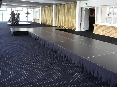 Portable stage system with black skirting arranged for indoor event use