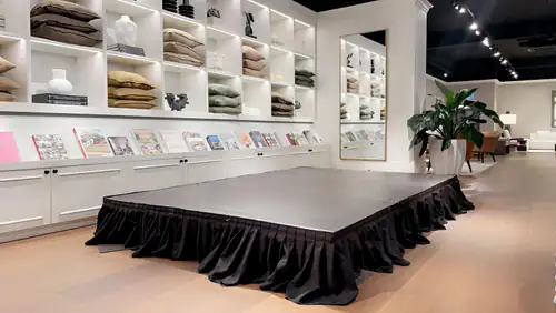 Portable stage platform with black skirting arranged for an indoor event or presentation setup