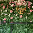 A vibrant green wall adorned with colorful flowers, complemented by a sleek table in front of it.