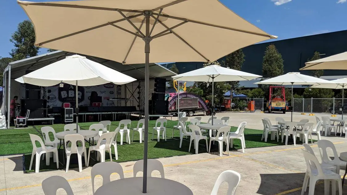 A round café table hire with tables and chairs and umbrellas.
