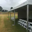 An 8m x 21m white tent with chairs set up on a grassy field.