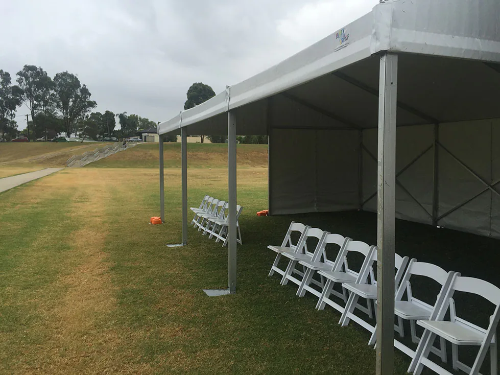 An 8m x 21m white tent with chairs set up on a grassy field.