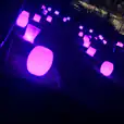 A group of purple stools in a dark area available for Glow Bongo Seat Hire.