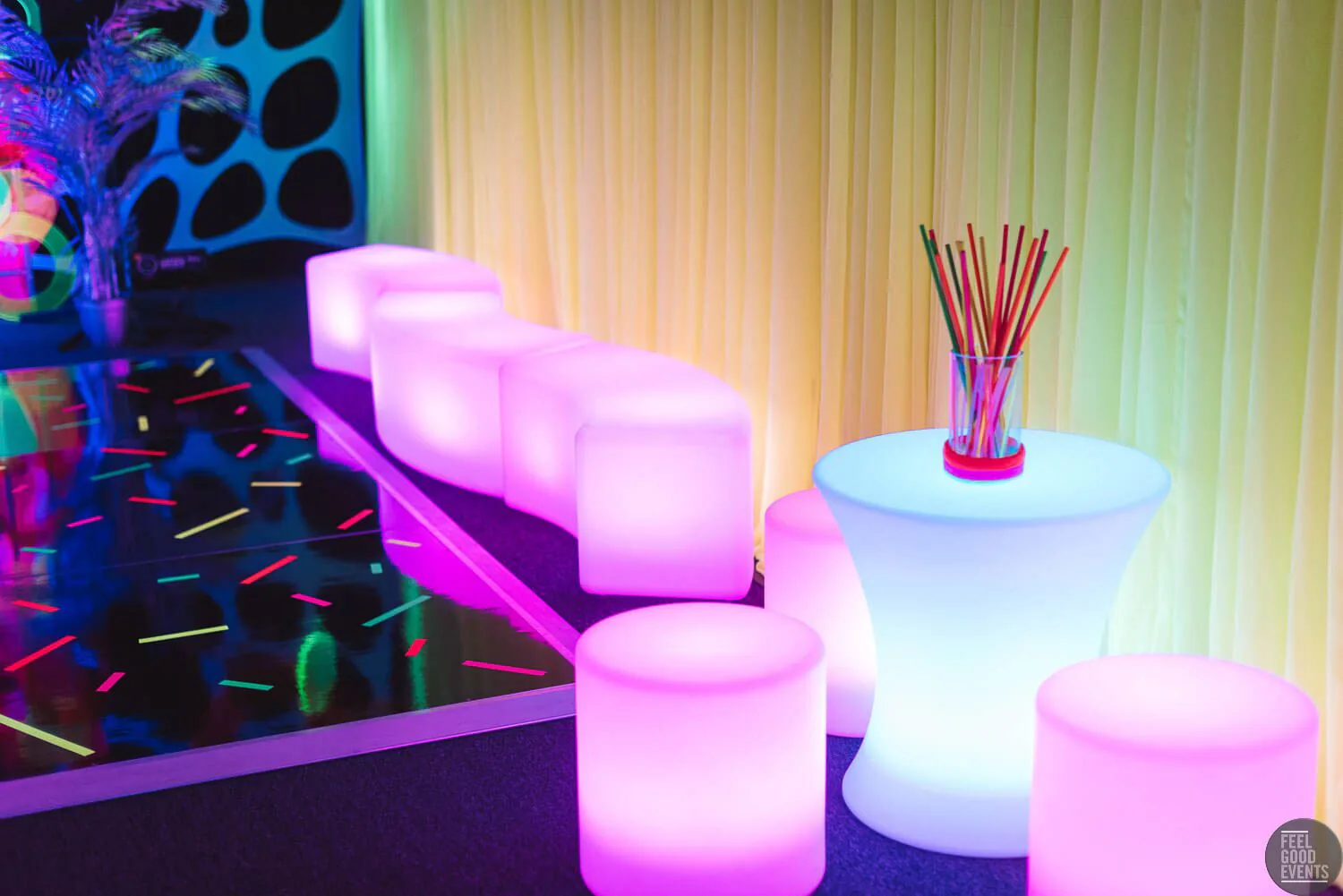 A vibrant space adorned with shimmering glow cylinder seats for hire, brightening the room with an array of colorful lights.