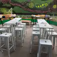 A set of white hairpin high bar stools in front of a green wall.