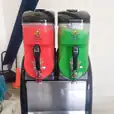 Two soda dispensers sitting on top of a table, offering a variety of drinks with Slushie Machine Hire: Pkg 4 - serving up to 180 Drinks.