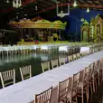 A timber trestle table, measuring 1.8m in length, set up in a large hall with a carousel for hire.