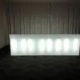 A straight white LED bar in a room with curtains, designed to glow.