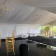 A white tent with gold chairs and tables, within a 6m x 30m - Framed Marquee.