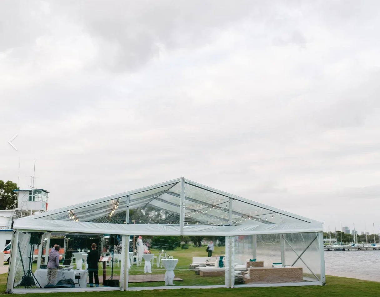 A 6m x 39m framed marquee wedding tent set up on a grassy area near the water.