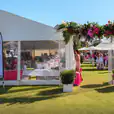 An 8m x 21m white tent with pink flowers in the middle of a grassy field.