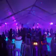 A group of people in an 8m x 21m - Framed Marquee with purple lights.