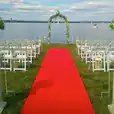 A wedding ceremony set up on a red carpet in front of a lake, featuring a stunning 7m long red carpet.