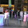 A group of mannequins in front of a Silver building.
