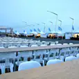 White tables and chairs, including Timber Trestle Table 2.4m Hire, are set up in front of a tent.