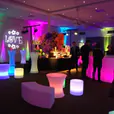 A room filled with Glow Cylinder Seats illuminated by colorful lights.