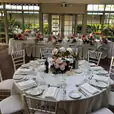A table set up with white Tiffany chairs and flowers.