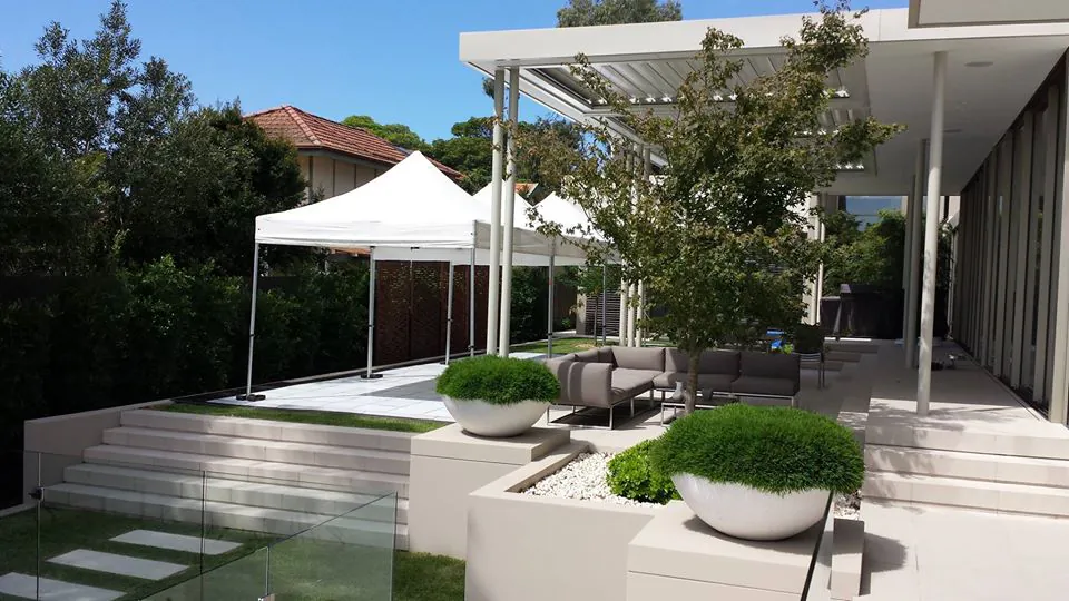 A modern backyard with a white tent and potted plants, featuring a 3mx3m Pop Up Marquee with a White Roof.