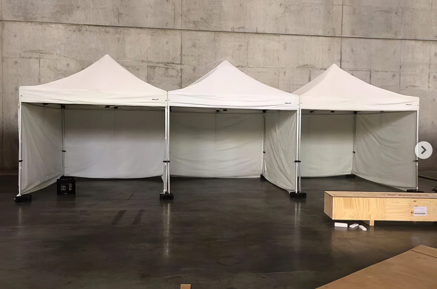 Three 3mx3m pop up marquees with walls on three sides set up in a warehouse.